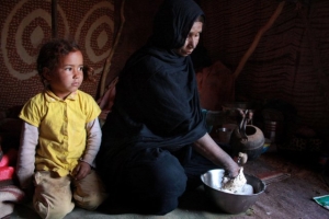 Ronia e sua neta durante o ritual de preparação do tradicional pão saaraui que cozinha sob as areias quentes do deserto. Foto: Laura Daudén. 