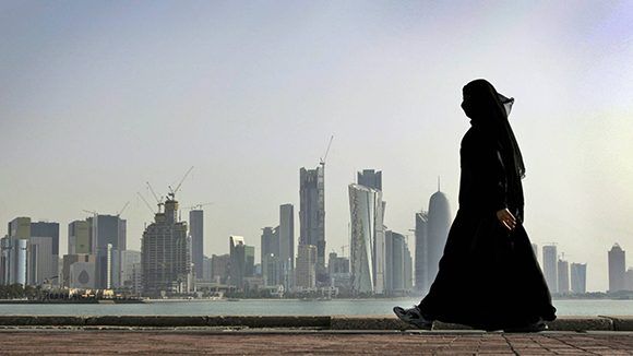 Uma mulher caminha em frente aos arranha-céus de Doha / Foto: AP