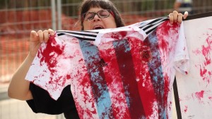 Uma manifestante segura uma camisa do time de futebol argentino, manchado de sangue, em protesto contra o amistoso dos albicelestes com o regime de Israel
