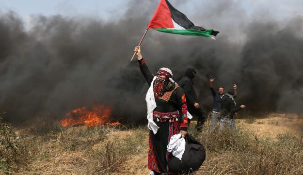 Mulher palestina ergue bandeira durante os protestos, em 27 de abril de 2018. / Foto: Ibrahim Abu Mustafa - Reuters